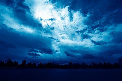 Clouds Spiraling Above Dark Lit Lake (Blue Shade Photo)