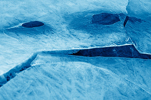 Rock Face Emerges Among Cracked Frozen Ice (Blue Shade)