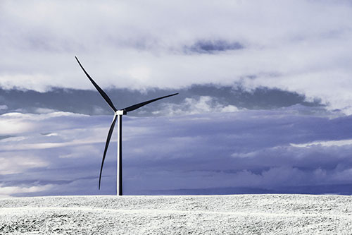 Lone Wind Turbine Standing Along Dry Prairie Horizon (Blue Tint Photo)