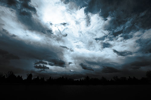 Clouds Spiraling Above Dark Lit Lake (Blue Tone Photo)