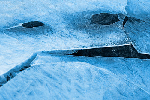 Rock Face Emerges Among Cracked Frozen Ice (Blue Tone)