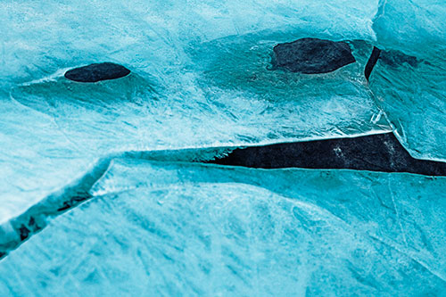 Rock Face Emerges Among Cracked Frozen Ice (Cyan Tint)