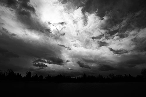 Clouds Spiraling Above Dark Lit Lake (Gray Photo)
