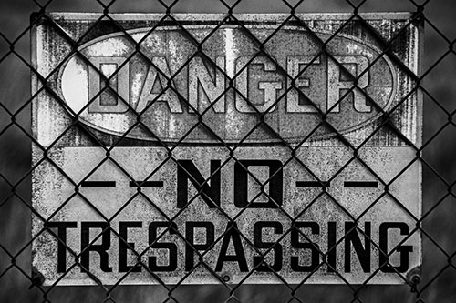 Dirty Danger No Trespassing Sign Behind Chain Link Fence (Gray)