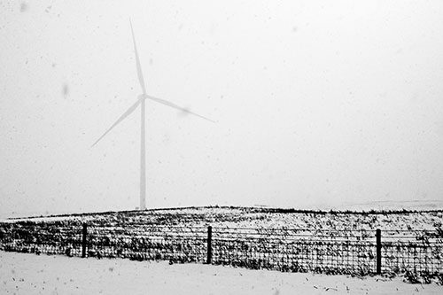 Fenced Wind Turbine Among Blowing Snow (Gray Photo)