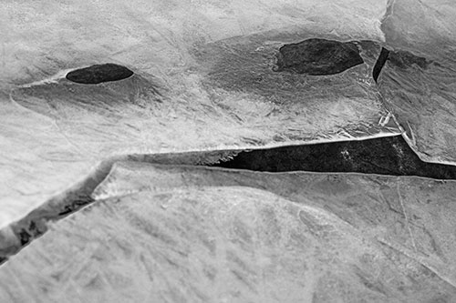 Rock Face Emerges Among Cracked Frozen Ice (Gray)