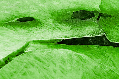 Rock Face Emerges Among Cracked Frozen Ice (Green Tone)