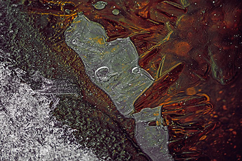 Frozen Bubble Eyed Ice Face Figure Along River Shoreline (Orange Tint)