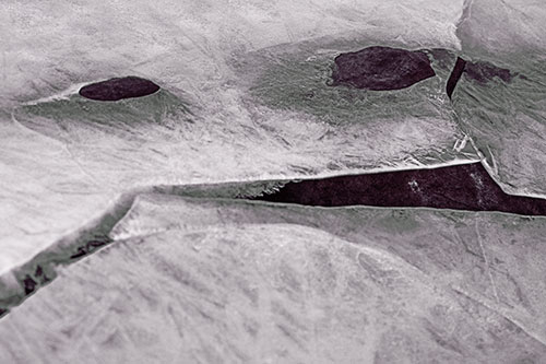 Rock Face Emerges Among Cracked Frozen Ice (Orange Tint)