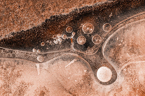 Ice Bubbles Among Frozen Soil Crevice (Orange Tone Photo)