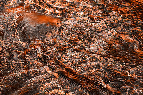 Large Algae Rock Creating River Water Ripples (Orange Tone Photo)