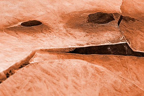 Rock Face Emerges Among Cracked Frozen Ice (Orange Tone)