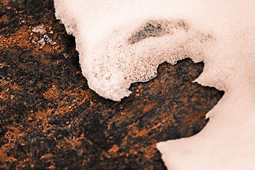 Screaming Snow Face Slowly Melting Atop Rock Surface (Orange Tone Photo)