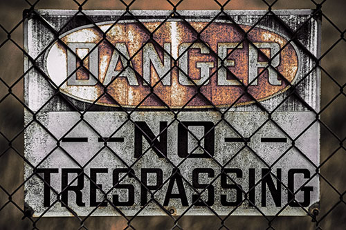 Dirty Danger No Trespassing Sign Behind Chain Link Fence (Red Tint)