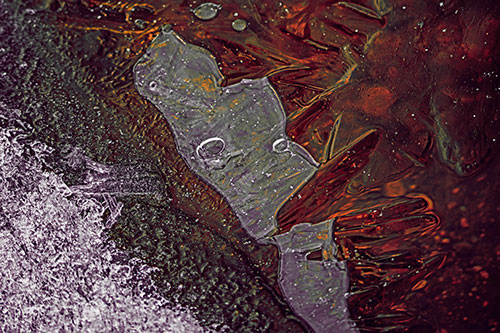 Frozen Bubble Eyed Ice Face Figure Along River Shoreline (Red Tint)