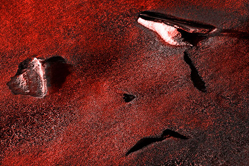 Sad Teardrop Ice Face Appears Atop Frozen River (Red Tone Photo)