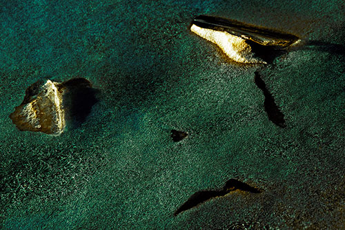 Sad Teardrop Ice Face Appears Atop Frozen River (Yellow Tint)